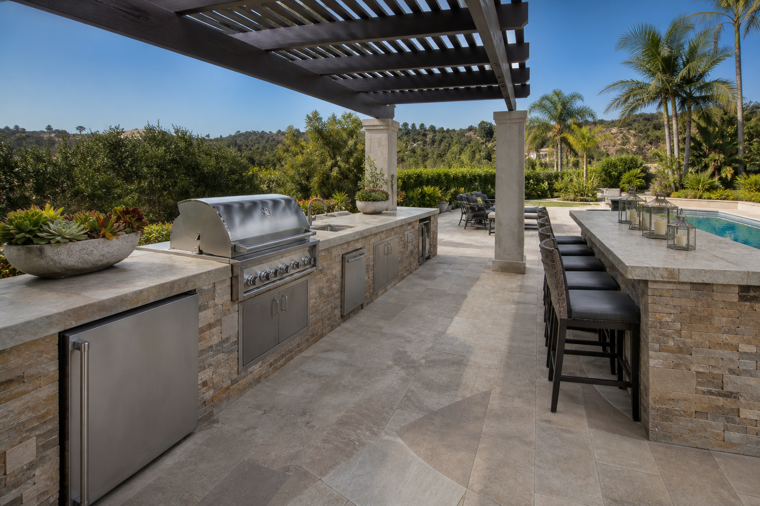 Full outdoor kitchen with long masonry counter and pool beyond
