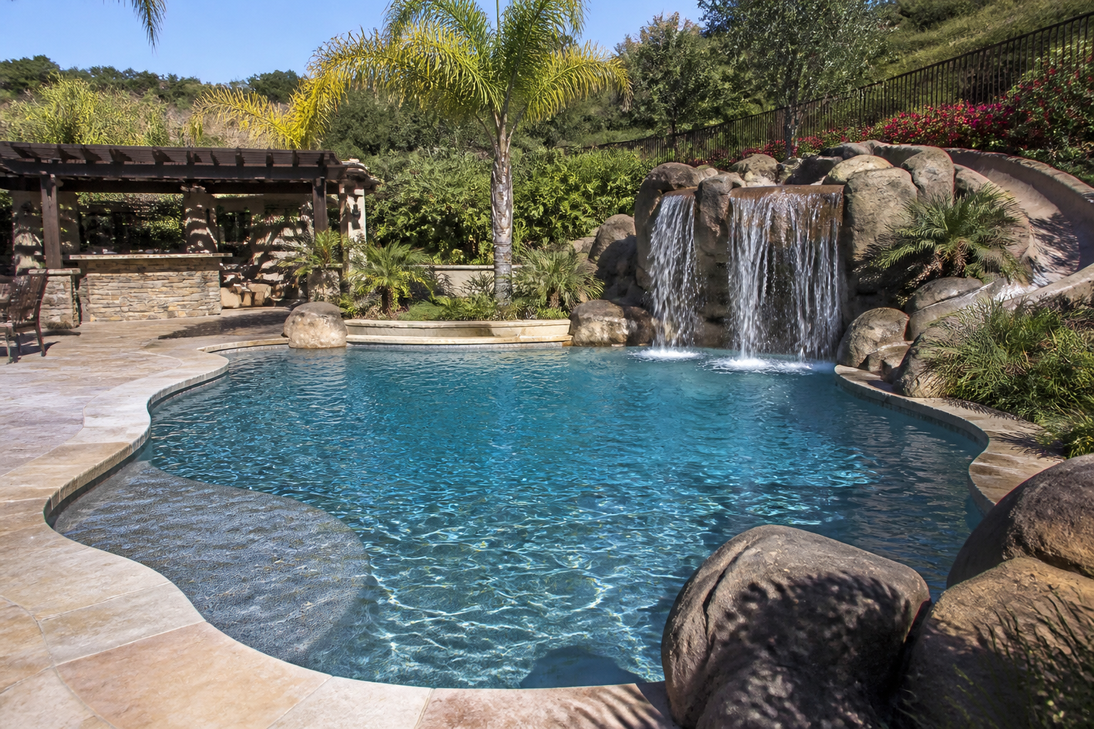 Pebble finish swimming pool with rock waterfall feature